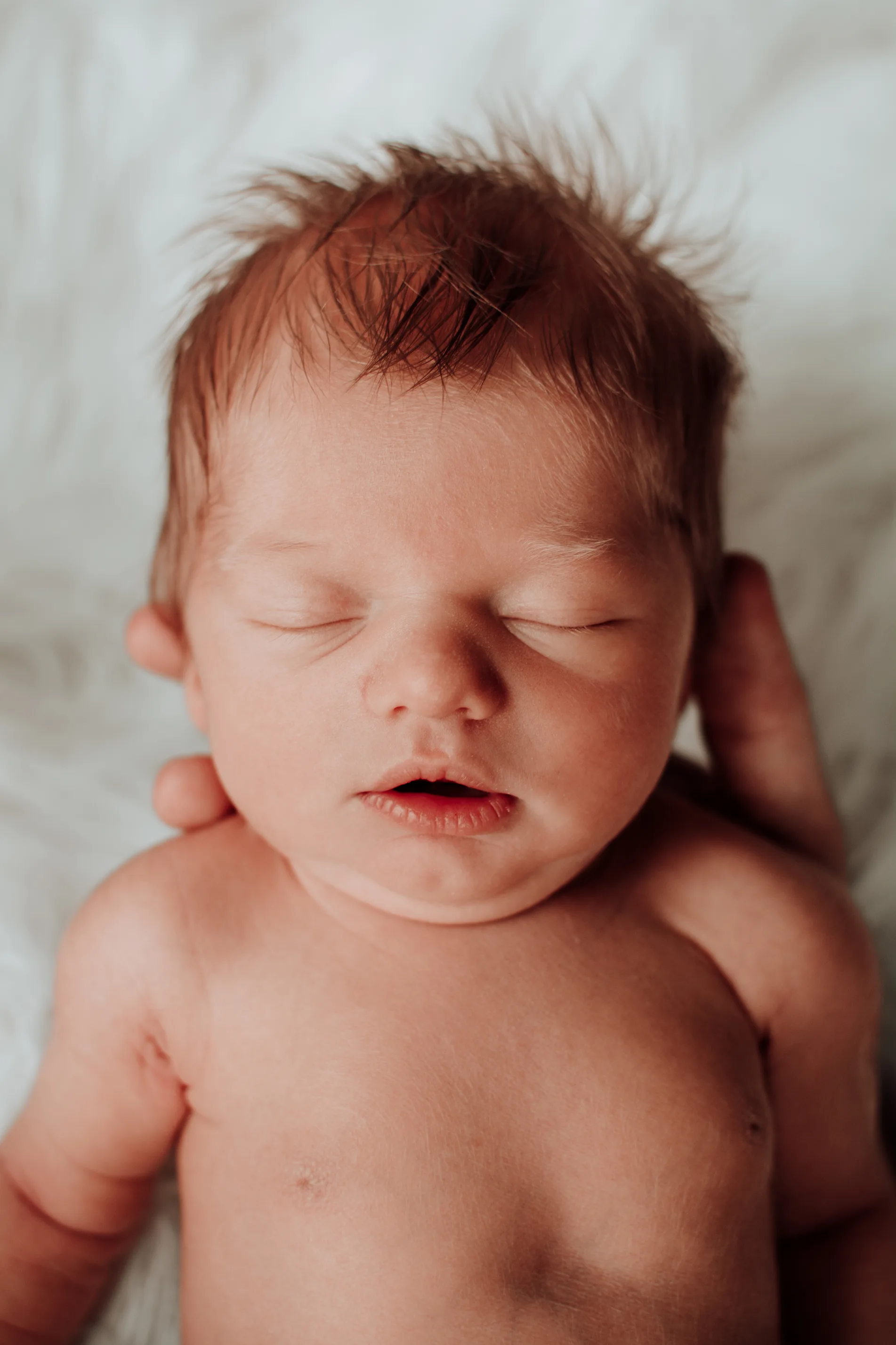 Newborn foto van een zeer jonge baby liggend in de hand van mama