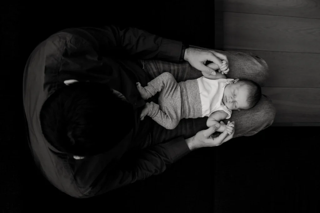 Vader houdt baby op zijn schoot tijdens newbornshoot